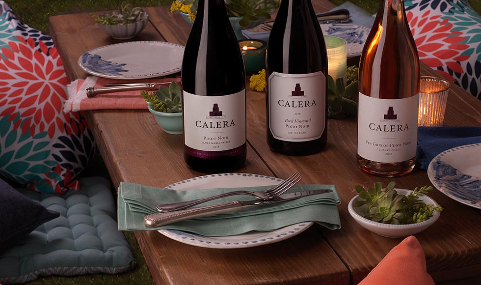Three bottles of Calera Pinot Noir on a picnic table