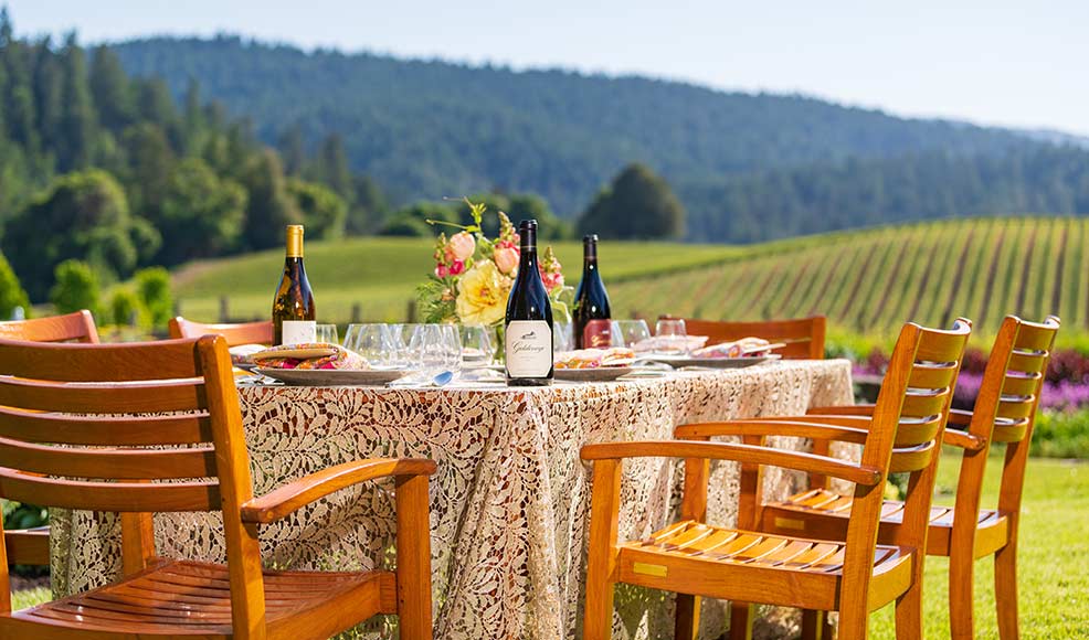 Bottles of Goldeneye and Migration wines on a table overlooking a vineyard